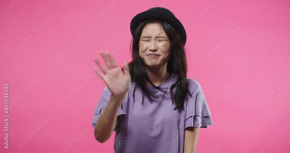 Close up portrait of happy pretty Asian young woman in black hat stands isolated on rosy pink background denying and rejecting something, waving hand and covering ears with hands doesn't want to hear Close up portrait of happy pretty Asian young woman in black hat stands isolated on rosy pink background denying and rejecting something, waving hand and covering ears with hands doesn't want to hear