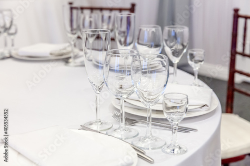 Fancy table set for dinner with napkin glasses in restaurant  luxury interior background. Wedding elegant banquet decoration and items for food arranged by catering service on white tablecloth table.