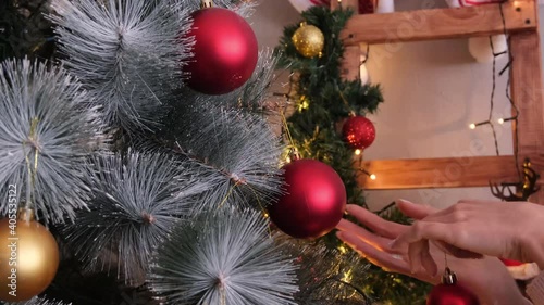 Women's hands without a face decorate the Christmas tree for the holiday. Christmas tree in toys and garlands.