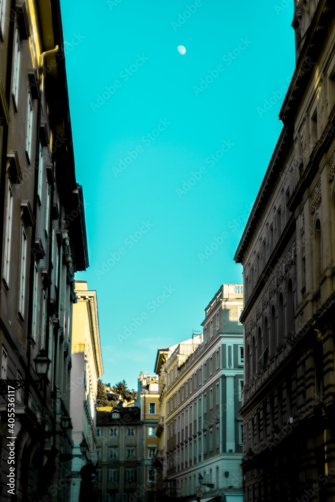 Vista prospettiva verticale di una strada di Trieste, edifici storici, cielo azzurro