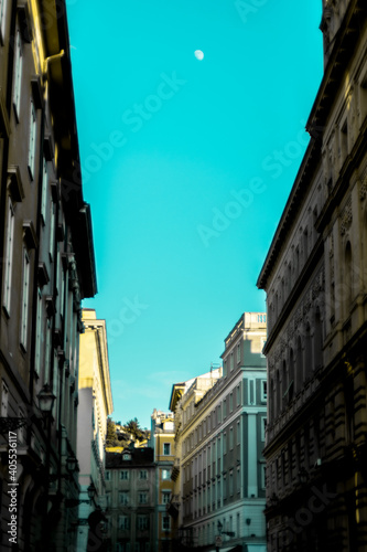 Vista prospettiva verticale di una strada di Trieste, edifici storici, cielo azzurro