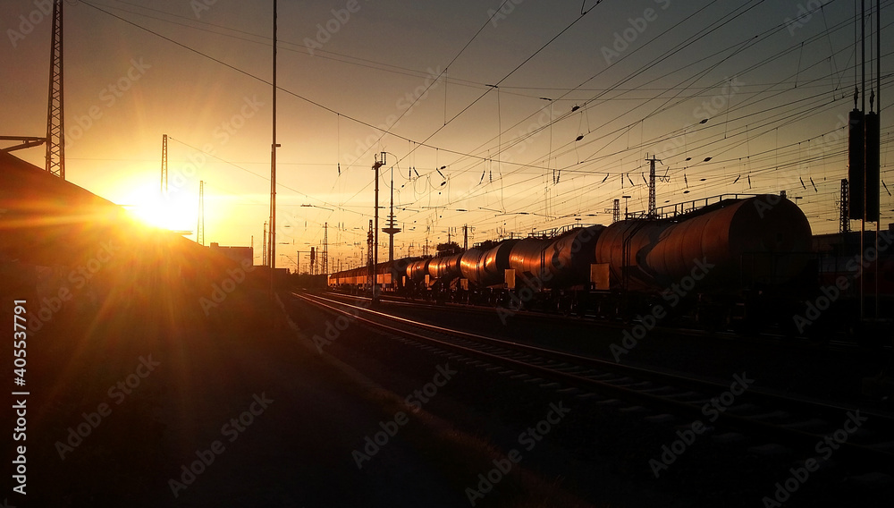 Freight train transporting goods on railroad towards glowing rusty evening sky. Powering industry and economy in a world of globalisation.