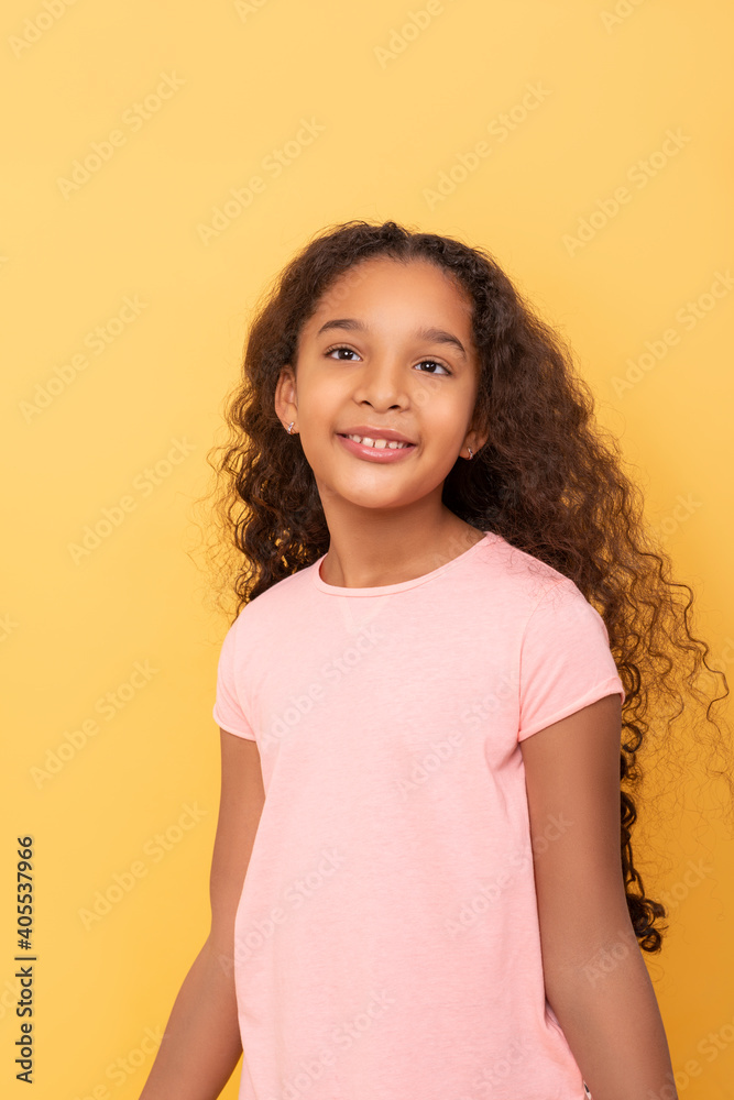 Young smiling black girl with long curly hair wearing pink shirt on a ...