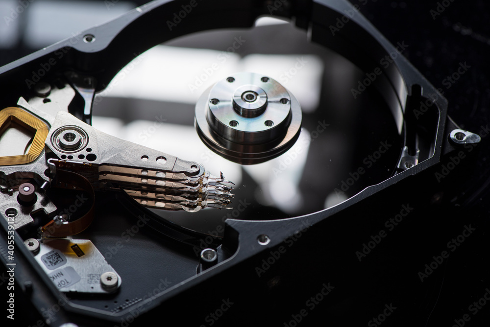 Component parts of a disassembled hard drive, close-up on a dark background. Component parts of a disassembled hard drive, close-up on a dark background.