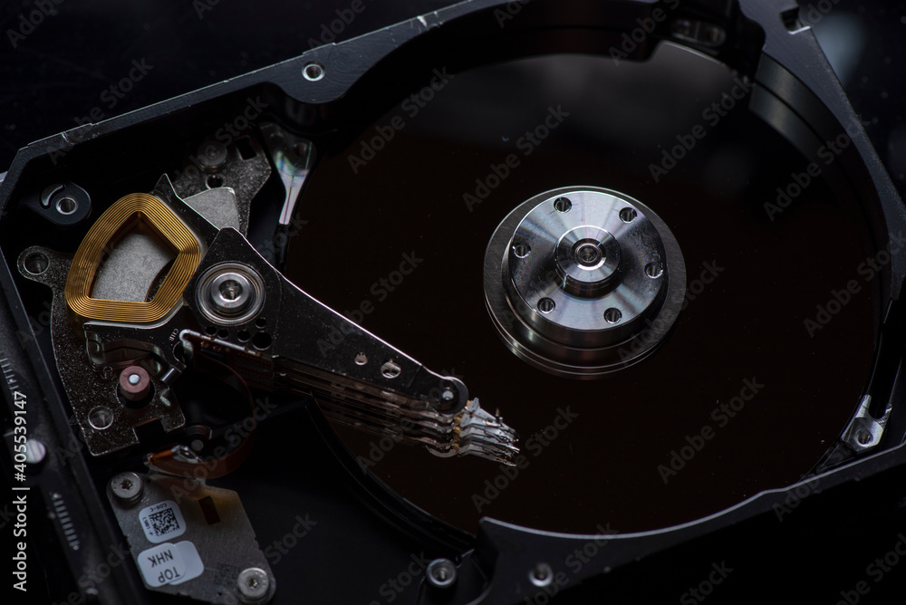 Component parts of a disassembled hard drive, close-up on a dark background. Component parts of a disassembled hard drive, close-up on a dark background.