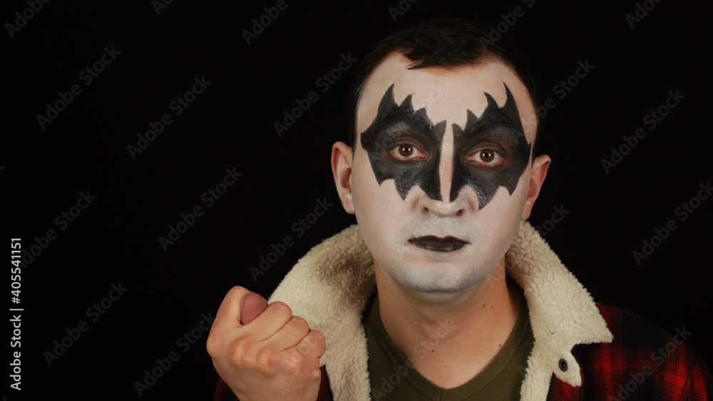 Man in demon makeup showing fig gesture on black background Man in demon makeup showing fig gesture on black background