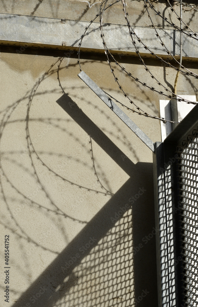 Fototapeta premium Barbwire and fence shadowplay on a wall