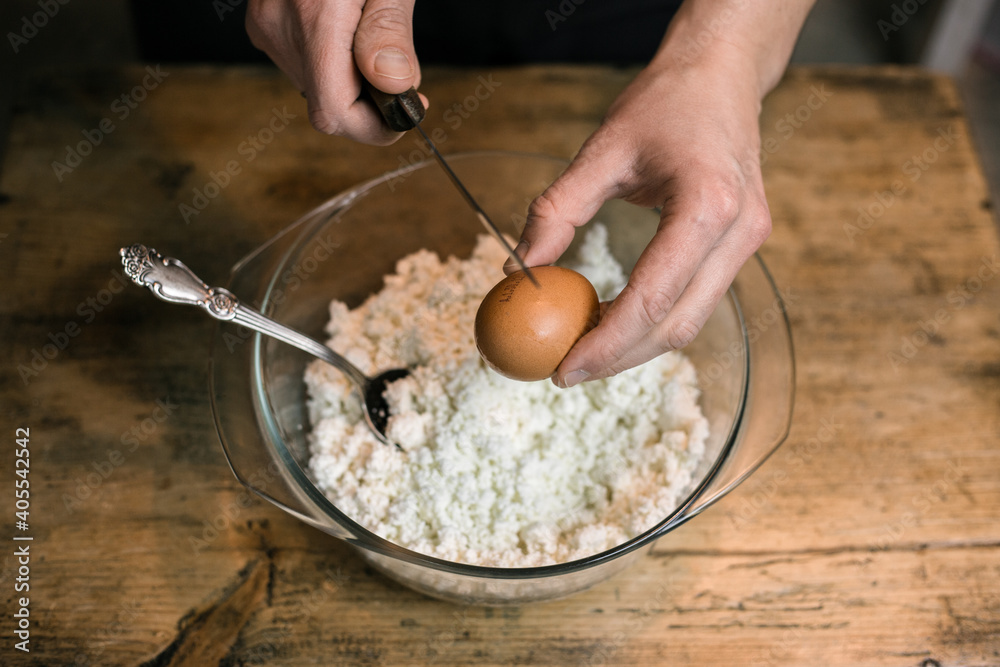 Breaks a chicken egg and adds to the curd Breaks a chicken egg and adds to the curd