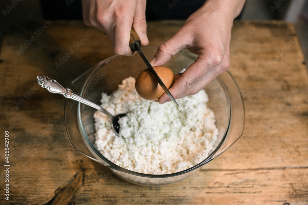 Breaks a chicken egg and adds to the curd Breaks a chicken egg and adds to the curd