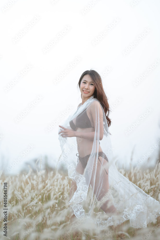 Naklejka premium Beautiful blonde women in a brown bikini on a brown meadow with white flowers in the summer evenings.