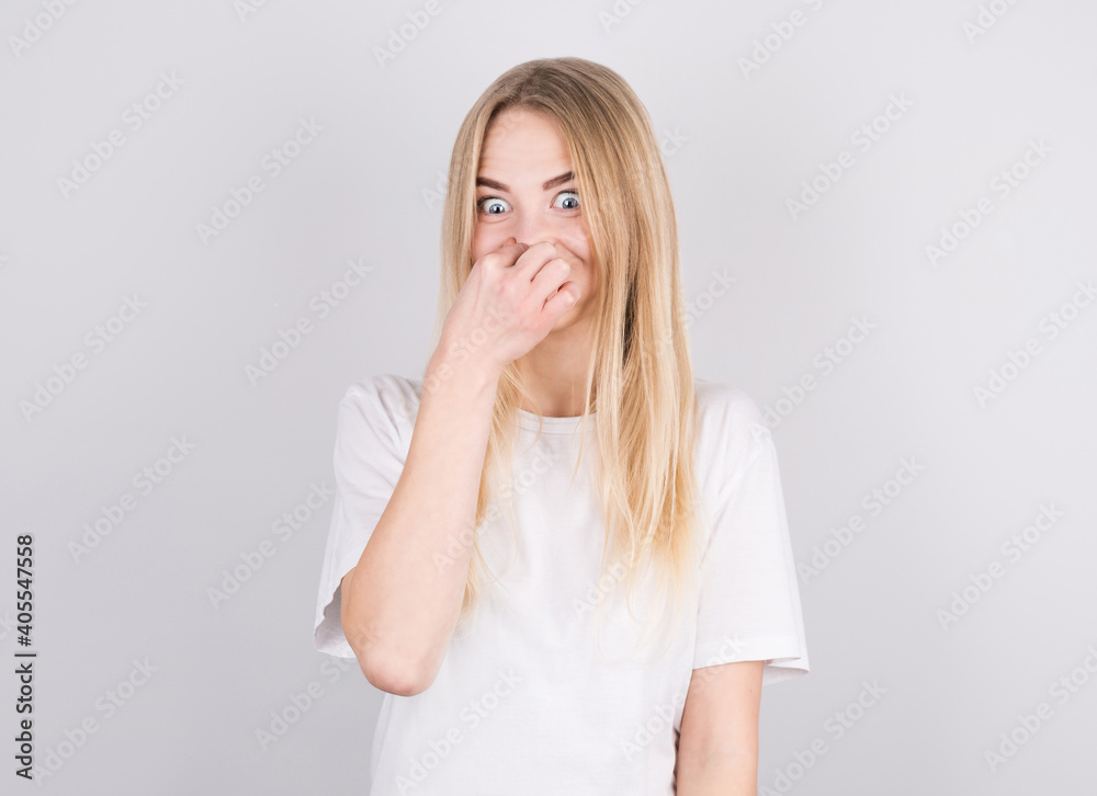 Young woman with disgust on his face pinches nose on white background. Negative emotion facial expression. Young woman with disgust on his face pinches nose on white background. Negative emotion facial expression.