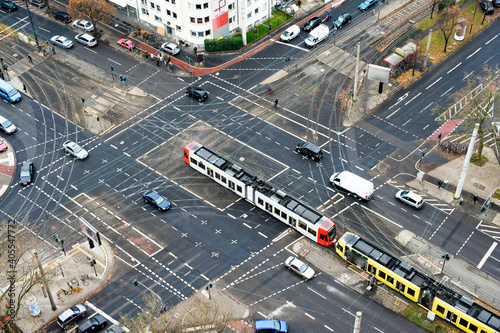 A city crossing with tram and cars seen from above.