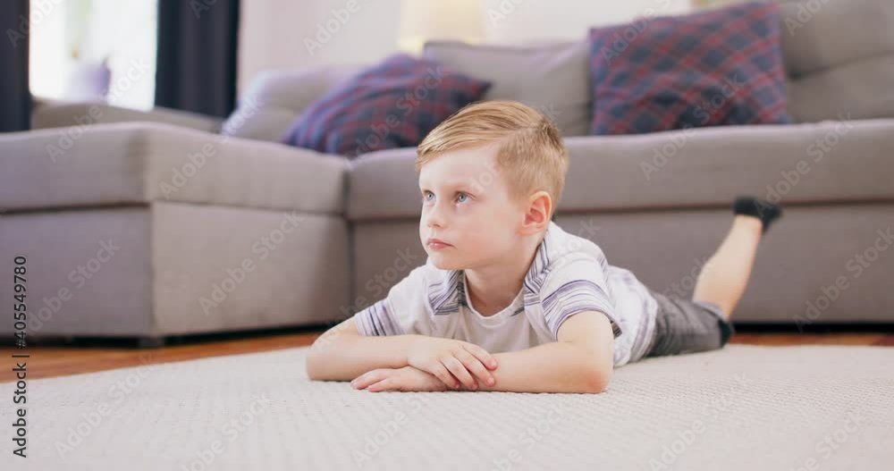 Cute little boy with blonde hair is lying on the floor staring at his favorite cartoon on the TV. Cute little boy with blonde hair is lying on the floor staring at his favorite cartoon on the TV.