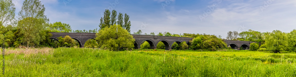 A panorama view along the banks of the River Nene towards the old railway viaduct at Thrapston, UK in springtime
