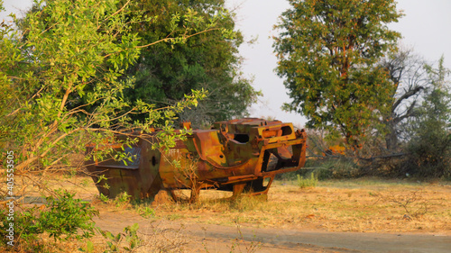 Old Rusted tanks in the bush of Angola, dating back to the South African, Angolese bush war, involving Cuban, Russian tanks, and vehicles. Green grass and trees surround the tanks.