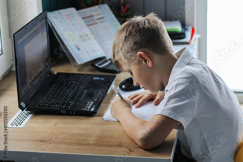 A boy learns lessons at home distance learning on a laptop