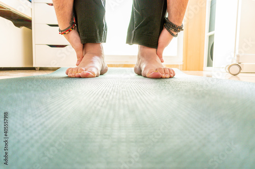 Feet of a man doing yoga on top of a mat