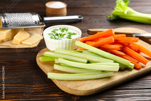 Celery and carrot sticks with dip sauce on wooden table