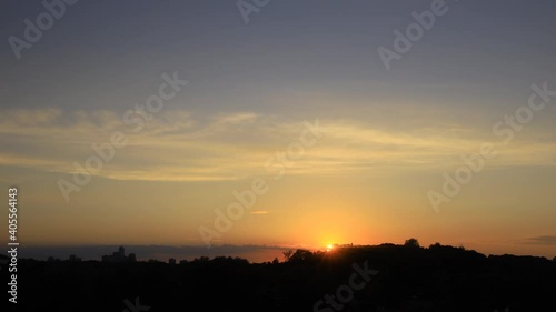 Time lapse of sunset with clouds and high rise building silhouettes on horizon 