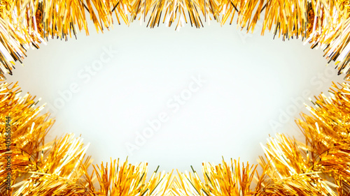 Close up frame of golden metal celebration tinsel white backdrop.Christmas New Year birthday garland decoration.Festive party decor.Sparkling invitation greeting card.Horizontal banner copy space