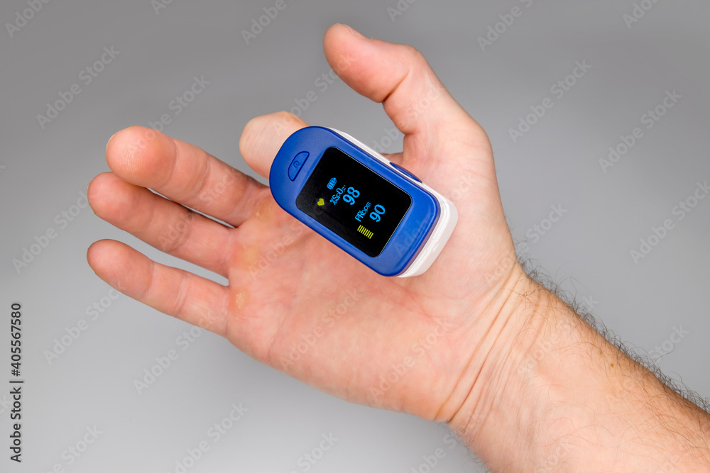 A pulse oximeter on the finger of a man's hand measures the amount of oxygen in the blood and the pulse. A pulse oximeter on the finger of a man's hand measures the amount of oxygen in the blood and the pulse.