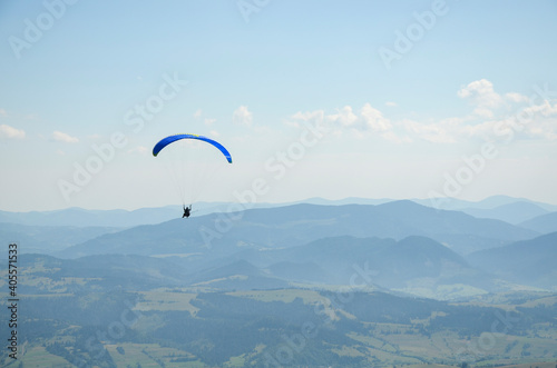 Paraglider flies in the sky over the mountains on a bright sunny day. Paragliding in the sky. Extreme sport. 