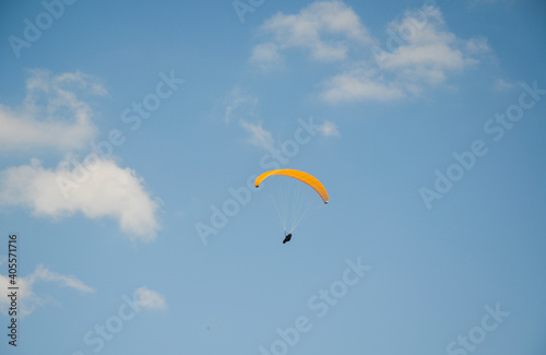 Paraglider flies in the sky over the mountains on a bright sunny day. Paragliding in the sky. Extreme sport.

