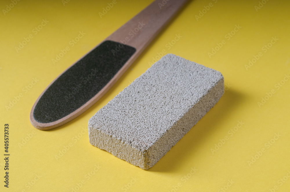 Pumice stone for the treatment of feet from calluses and a sponge on a yellow background Pumice stone for the treatment of feet from calluses and a sponge on a yellow background