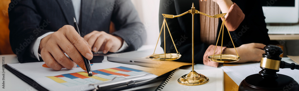 Business and lawyers discussing contract papers with brass scale on desk in office. Law, legal services, advice, justice and law concept picture with film grain effect Business and lawyers discussing contract papers with brass scale on desk in office. Law, legal services, advice, justice and law concept picture with film grain effect