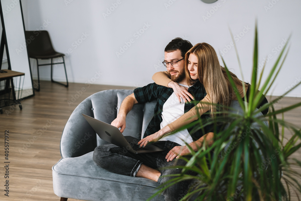 Young couple using laptop computer and resting on the sofa at home together. Young couple using laptop computer and resting on the sofa at home together.