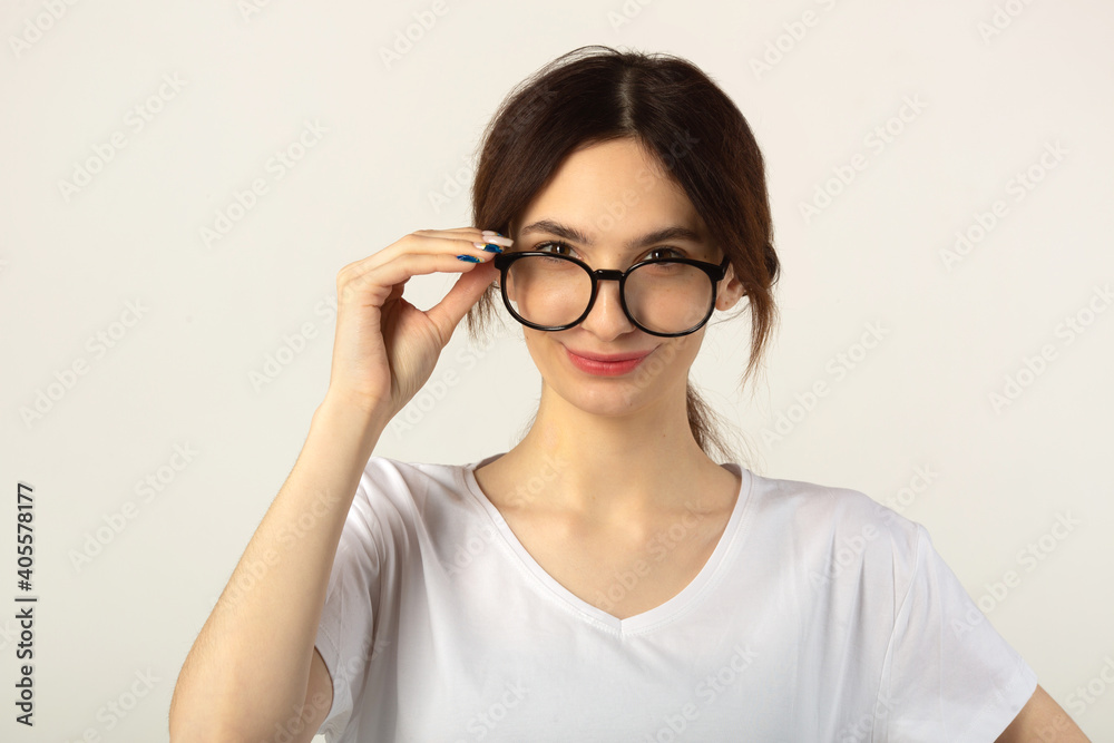 beautiful young woman in a white t-shirt on a white background wearing glasses