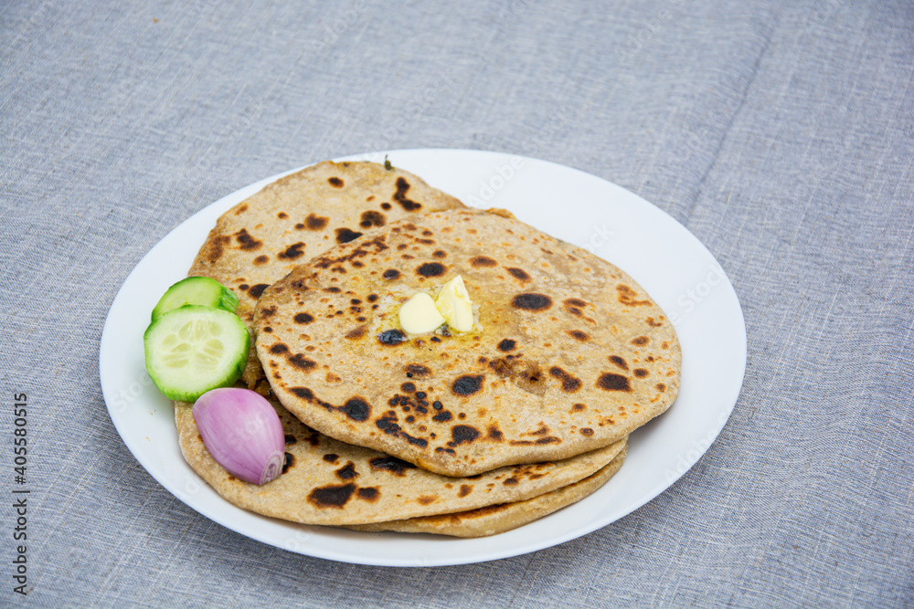 Aloo parotha in a white plate with onion, salad and broccoli fry with raita . An indian healthy breakfast Aloo parotha in a white plate with onion, salad and broccoli fry with raita . An indian healthy breakfast