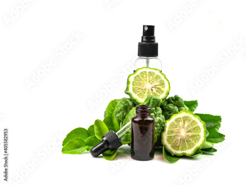 Bergamot essential oil in bottle and sliced fruit with leaves, isolated on white background.