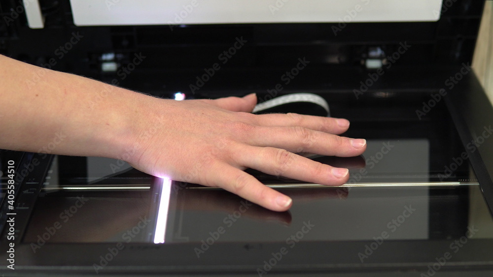 Hand scanning process. Scanner in operation scans a human hand with the lid open