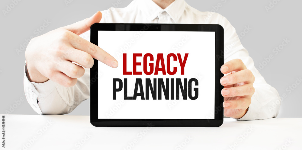 Text LEGACY PLANNING on tablet display in businessman hands on the white bakcground. Business concept