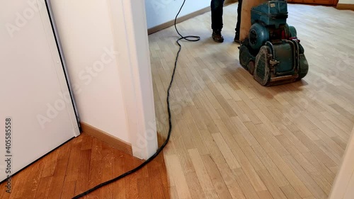 sanding wooden floor of parquet, with pad sander machine in an empty room during a renovation. Worker man for sand and refinish hardwood floors. top view