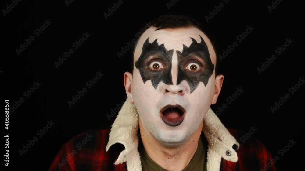 Emotionally scarred man in demon makeup is shocked on black background Emotionally scarred man in demon makeup is shocked on black background