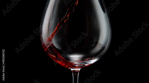 Pouring red wine into wine glass on a black background