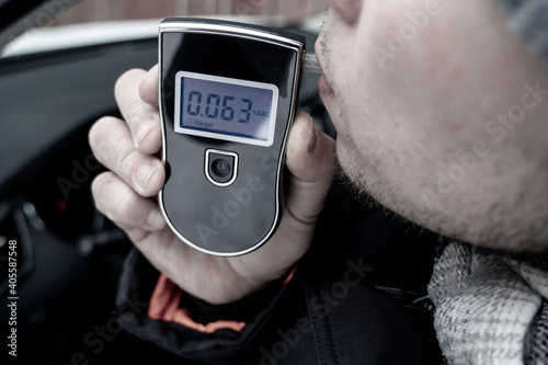 Bild auf Leinwand a man with a breathalyzer in the car, testing for alcohol and drug intoxication