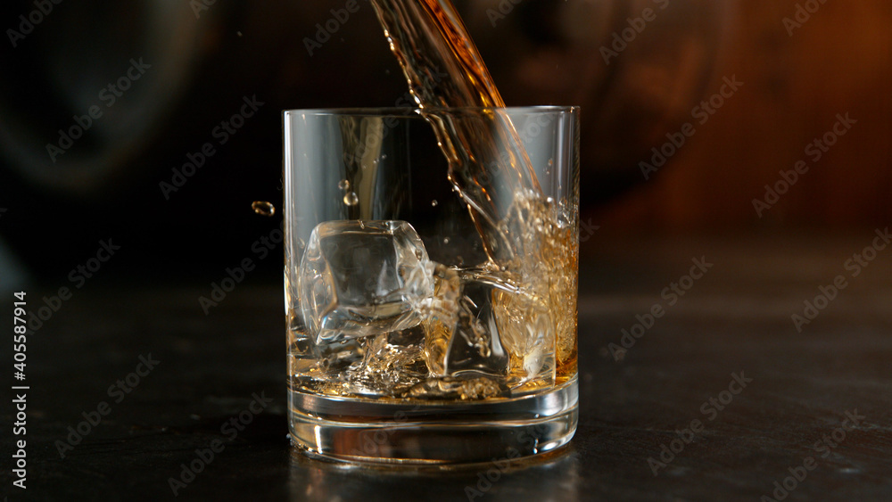Glass of whisky with splashing liquid and ice rocks inside. Glass of whisky with splashing liquid and ice rocks inside.