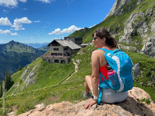 Wanderin mit Rucksack macht Pause vor einer Berghütte