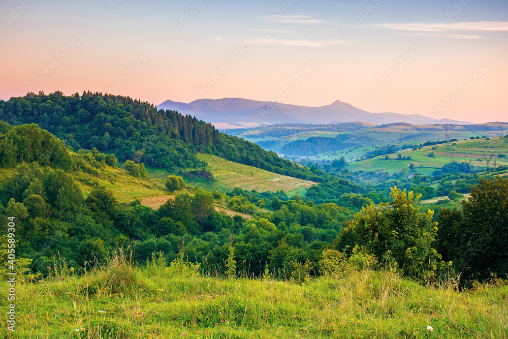 mountainous rural landscape at dawn. beautiful scenery with forests, hills and meadows in morning light. ridge with high peak in the distance. village in the distant valley mountainous rural landscape at dawn. beautiful scenery with forests, hills and meadows in morning light. ridge with high peak in the distance. village in the distant valley