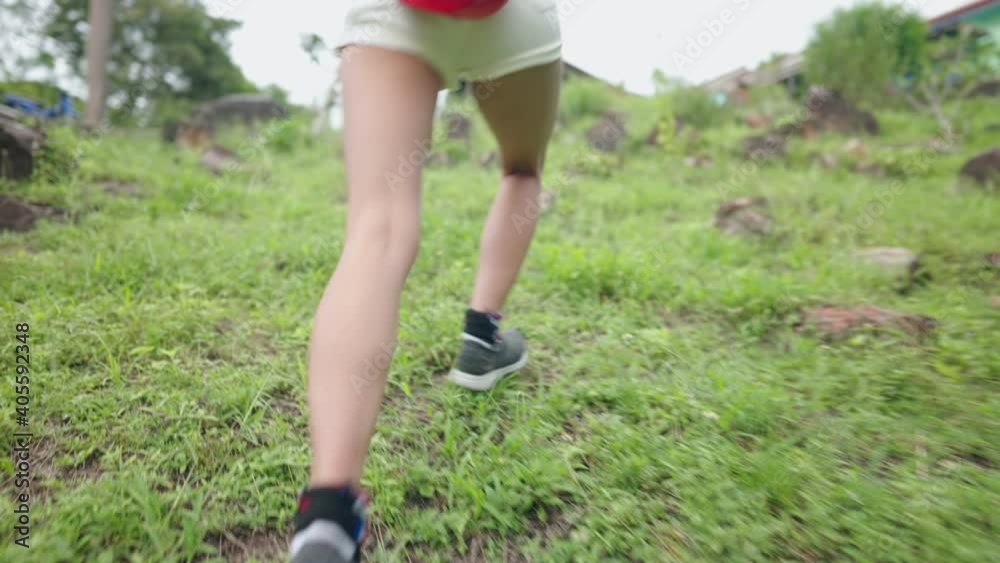 Low angle shot of young female legs walking up hill on weekend hiking, trekking on green grass path, extreme adventure outdoor activities, view from behind camera following model, national park Low angle shot of young female legs walking up hill on weekend hiking, trekking on green grass path, extreme adventure outdoor activities, view from behind camera following model, national park