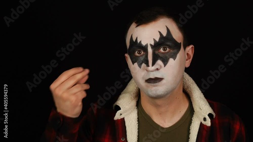 Man in scary demon makeup snapping fingers