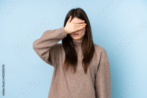 Young Ukrainian teenager girl wearing a sweater over isolated blue background covering eyes by hands. Do not want to see something