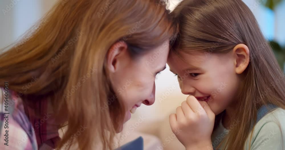 Joyful mom sitting with little girl on couch hugging and cuddling Joyful mom sitting with little girl on couch hugging and cuddling