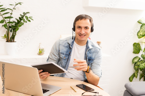 Happy young man smiling, as he works on his laptop to get all his business done early in the morning
