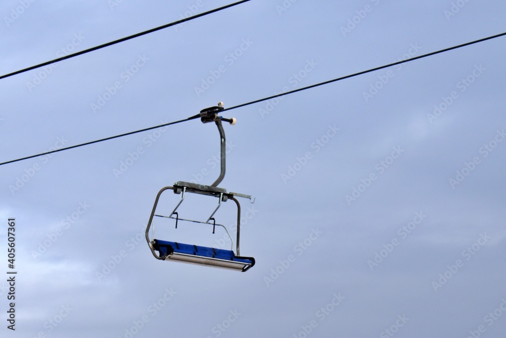 empty ski lift seats on blurred sky background