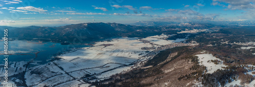 Wide panorama of lake cerknica on a cold winter day, visible lake with water and snow on the fields. Ridge of Slivnica mountain in the foreground, looking towards Nanos