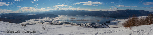 Fototapeta Naklejka Na Ścianę i Meble -  Wide panorama of lake cerknica on a cold winter day, visible lake with water and snow on the fields. Slope of Slivnica mountain in the foreground.